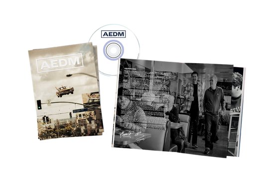 Een boek met de tekst 'AEDM' en een zwevende auto, een CD en een open boek met twee mannen in een diner.