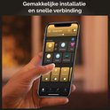 Een hand houdt een smartphone vast waarop de Philips Hue app met verschillende verlichtingsscènes wordt getoond.