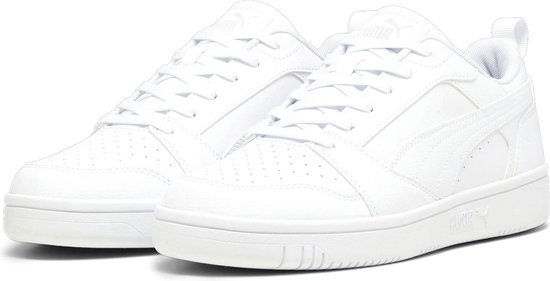 Een paar witte Puma sneakers, de voorste is schuin van voren gezien.