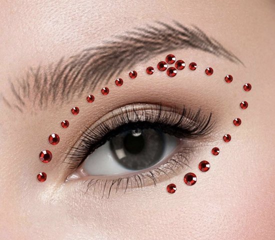 Rode glittersteentjes aangebracht rondom een oog, boven de wenkbrauw en onder het oog.