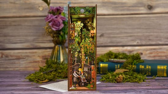 Boekensteun "The Secret Garden" met tuinscène, geflankeerd door mos en boeken, op een houten ondergrond.