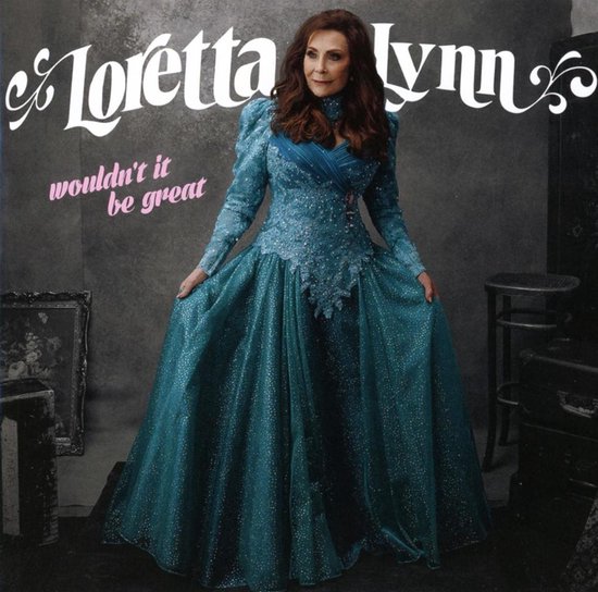 Loretta Lynn in een glinsterende, turquoise jurk met pofmouwen en een hoge hals.
