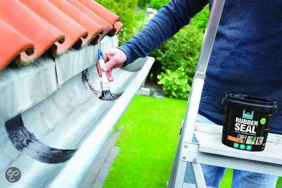 Man brengt met kwast zwarte rubbercoating aan in een dakgoot, ladder ernaast.