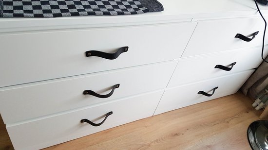 Witte ladekast met zwarte leren greepjes en zilverkleurige bevestiging.