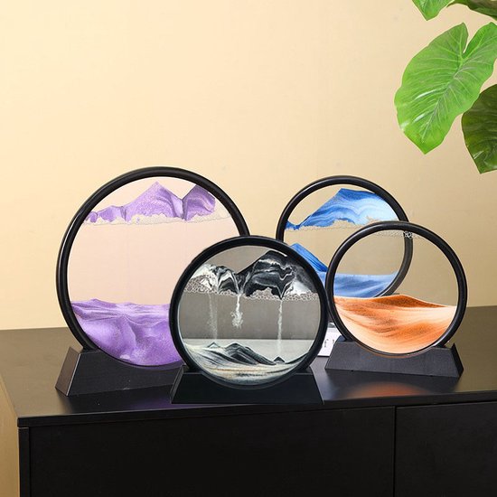 Quatre œuvres d'art en sable rondes avec du sable violet, bleu et orange ; une avec du noir et de l'or.