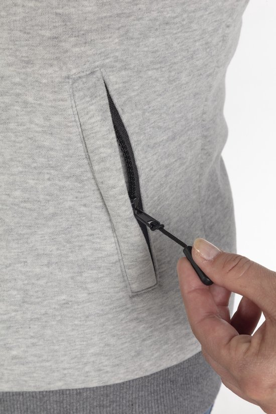 Close-up van een hand die de rits van een opgestikte zak op een grijze hoodie opent.