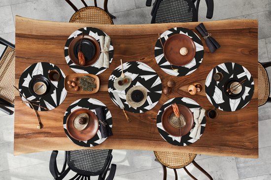 Table à manger dressée avec six sets de table ronds à motif avion en papier noir et blanc.