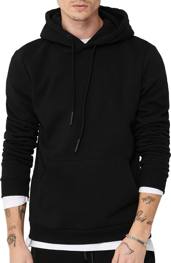 Man met kort geschoren haar en tatoeages, draagt een zwarte hoodie met witte longsleeve.