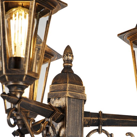 Gedetailleerde opname van de decoratieve kroon en de lantaarnkoepel van een antieke lamp.