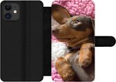 Bookcase Geschikt voor iPhone 12 Pro telefoonhoesje - Een Teckel puppy op een roze deken - Met vakjes - Wallet case met magneetsluiting