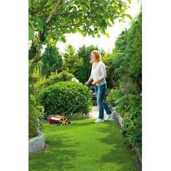 Vrouw maait met een rode cilindermaaier met gele wielen in een groene tuin.