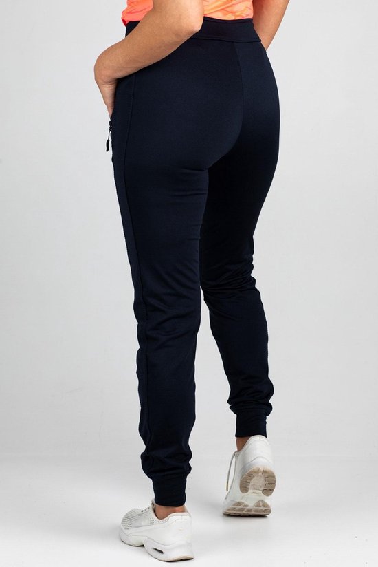Draagt een donkerblauwe joggingbroek, achterkant zichtbaar.