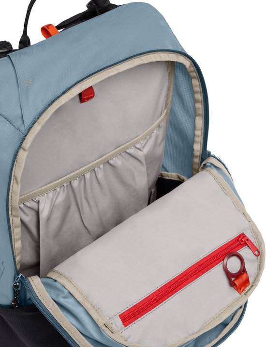 Open blauwgrijze rugzak met beige voering en een rood met zwarte rits.