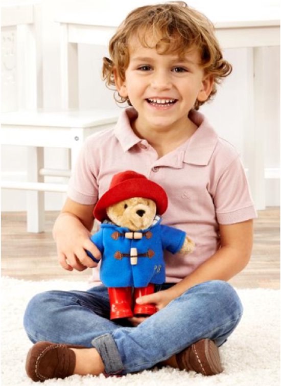 Jongen met Paddington Beer knuffel in blauwe jas, rode hoed en laarsjes.