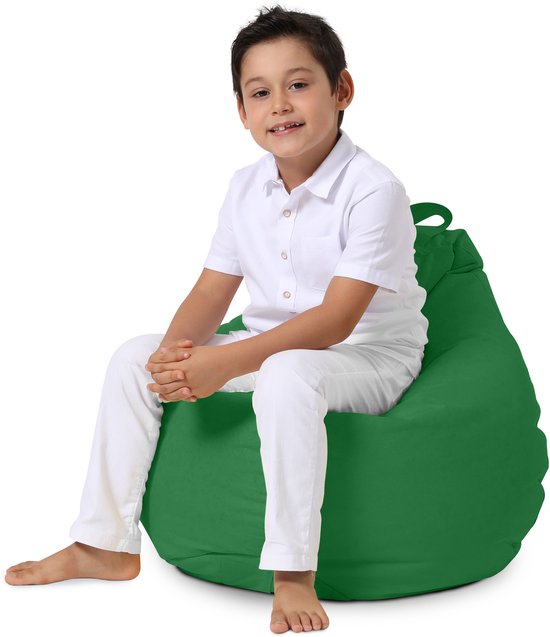 Jongen in wit shirt en broek zittend op een groene zitzak.