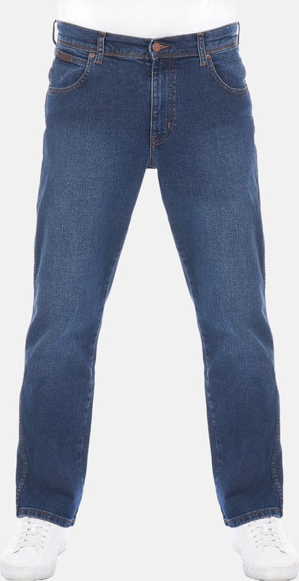 Man in een loszittende, blauwe Wrangler jeans met witte sneakers.