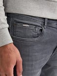 Close-up van de zak van een grijze jeans met een 'Petrol Industries' metalen logo.