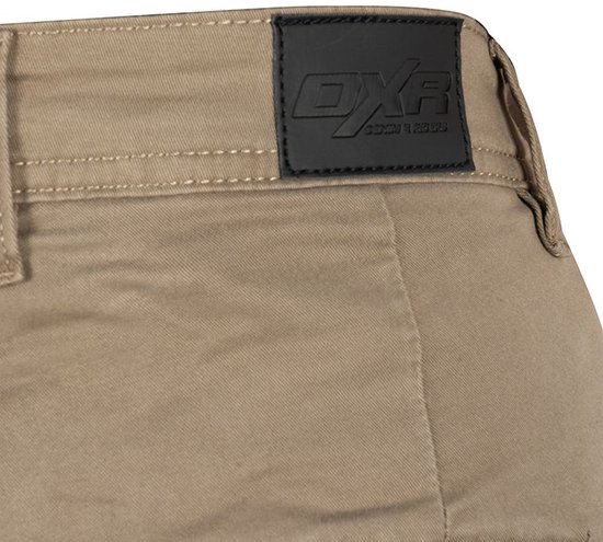 Close-up van een zwart 'DXR'-leren label op de tailleband van een bruine broek.
