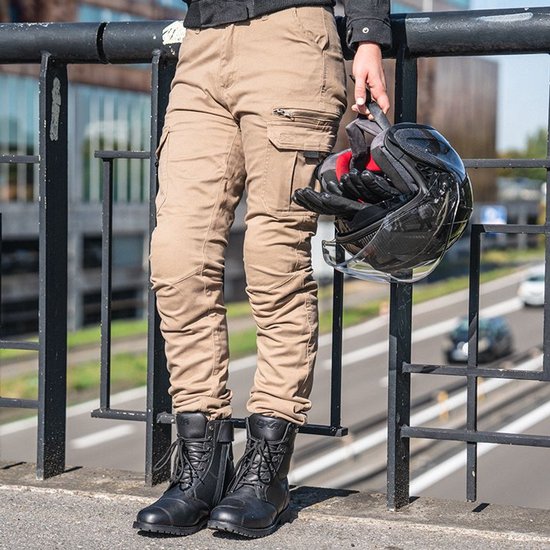 Vrouw op een zebrapad, draagt zandkleurige cargobroek en zwarte laarzen, houdt een helm vast.
