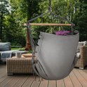 Grijze hangstoel met franjes, op een houten terras.