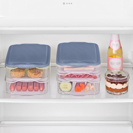 Deux boîtes de conservation alimentaires transparentes empilées remplies de charcuterie, saucisses, légumes et d'un dessert dans un réfrigérateur.