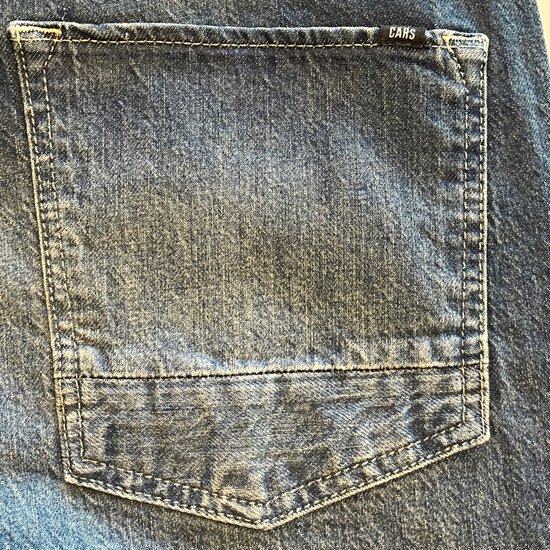 Detail van de achterzak van een spijkerbroek met een klein zwart 'CARS' label.