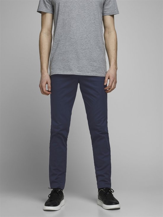 Model in een grijs T-shirt en een marineblauwe chino. De voorkant van de broek is zichtbaar.