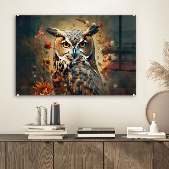 Gros plan d'un hibou aux yeux jaunes et aux plumes brunes, entouré de fleurs orange et rouges.