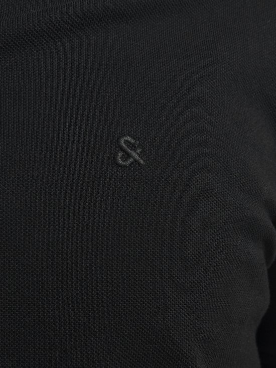 Close-up van het geborduurde zwarte & teken op een zwart poloshirt.