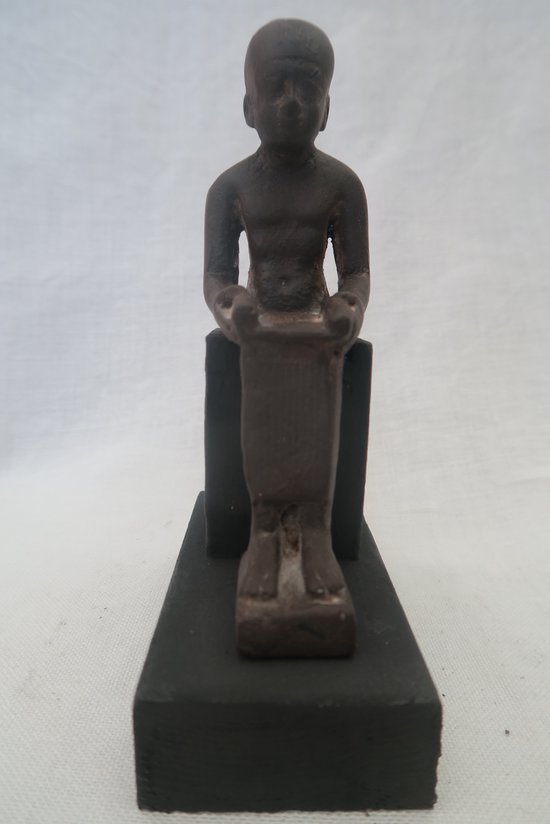Bruin beeldje van een staande figuur met gebogen armen, op een zwarte sokkel.