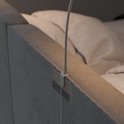 Close-up van een flexibele leeslamp bevestigd aan een stoffen hoofdbord.