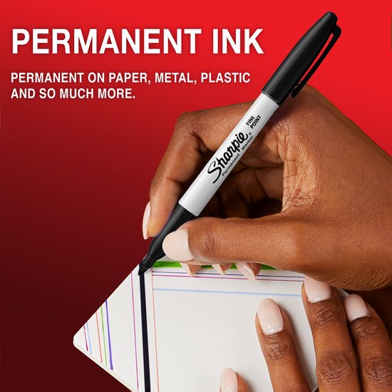 Een hand met een zwarte Sharpie marker schrijft op een stapel kaarten. Tekst "PERMANENT INK" bovenaan.