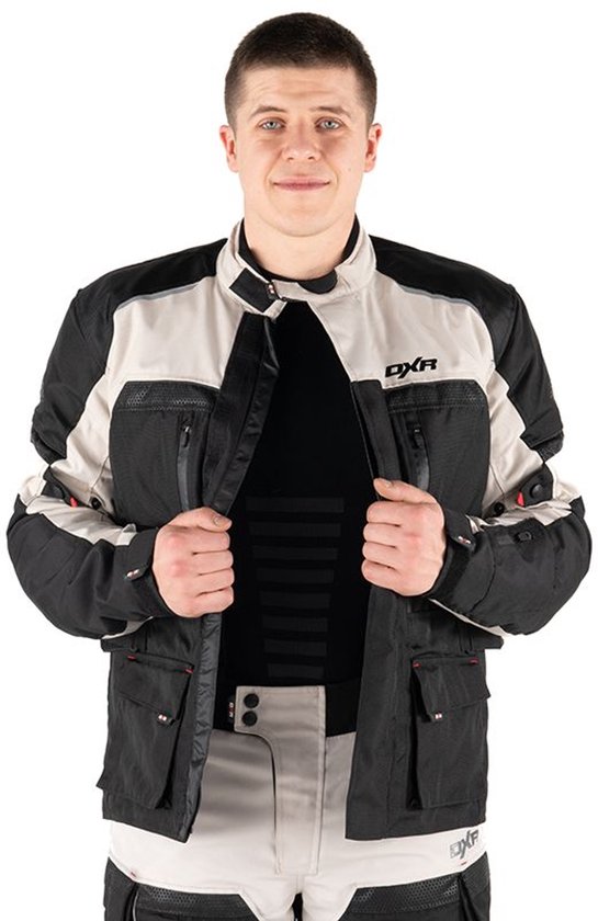 Man opent een DXR motorjas in zwart en grijs, met rode accenten. Hij toont de voering en drukknoopsluiting.