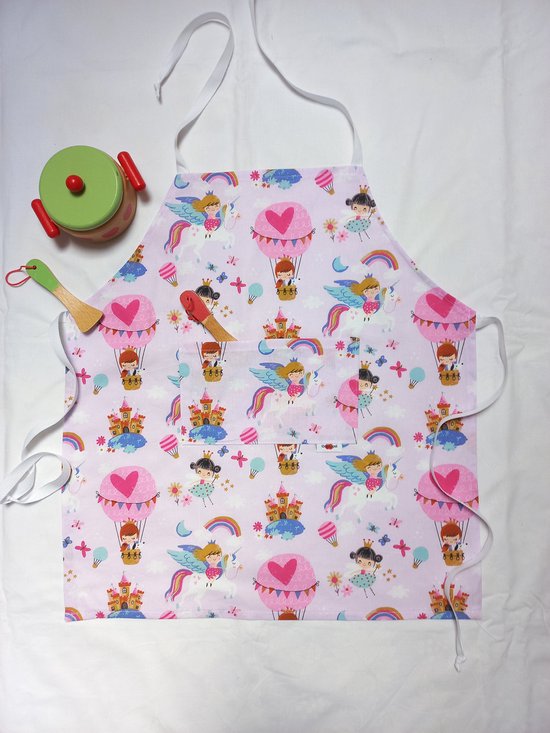 Roze schort met eenhoorns, kastelen, prinsessen en luchtballonnen. Een keukengerei ligt op het schort.