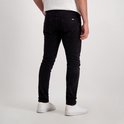 Man met zwarte corduroy broek en witte sneakers, zichtbaar van achteren.