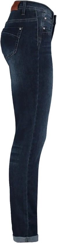 Zij-aanzicht van een donkerblauwe skinny jeans met opgerolde broekspijpen en een leren label aan de achterkant.