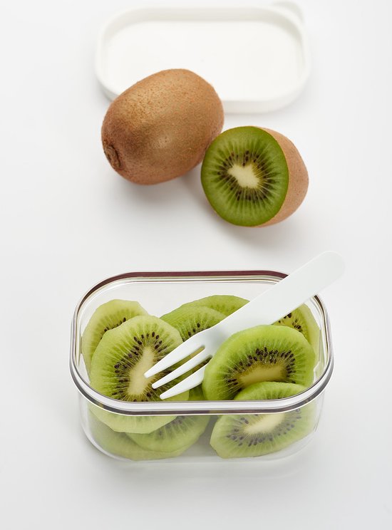 Boîte à lunch en verre remplie de tranches de kiwi, avec une fourchette blanche et un couvercle détaché à côté.