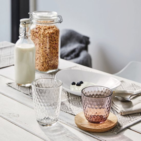 Deux verres à eau sur une table, un rose et un transparent, à motif nid d'abeille.