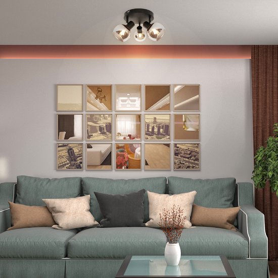 Zwarte plafondlamp met drie spots, boven een sofa in een woonkamer.