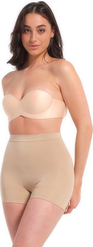 Vrouw met donker haar in beige corrigerende shorts en een strapless beha. De shorts hebben een hoge taille en een opengewerkt patroon op de heupen.