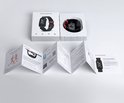 Uitgepakte rode en zwarte smartwatch met beschermende verpakking en handleidingen.