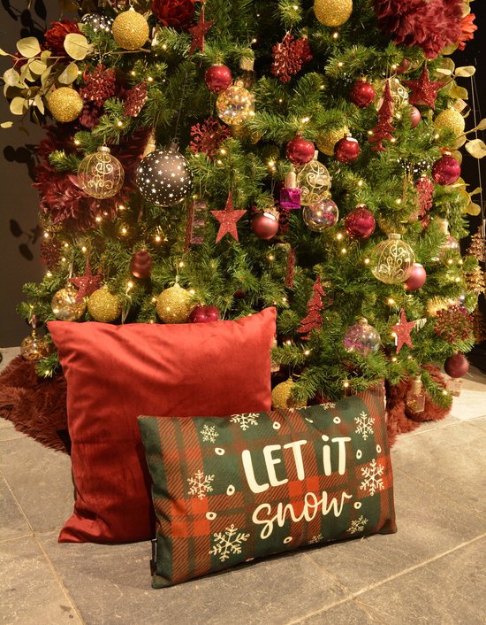 Kerstboom versierd met ballen, lichten en decoraties, met twee kussens ervoor. Een rood fluwelen kussen en een groen geruit kussen met witte tekst 'LET IT snow'.