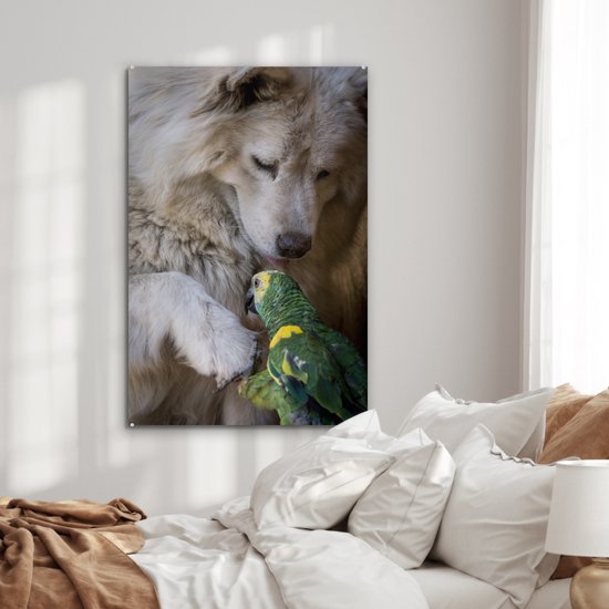 Een witte hond en een groene papegaai op een glasafbeelding boven een bed.