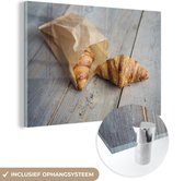MuchoWow® Glasschilderij 150x100 cm - Schilderij acrylglas - Croissant in papieren zak - Foto op glas - Schilderijen