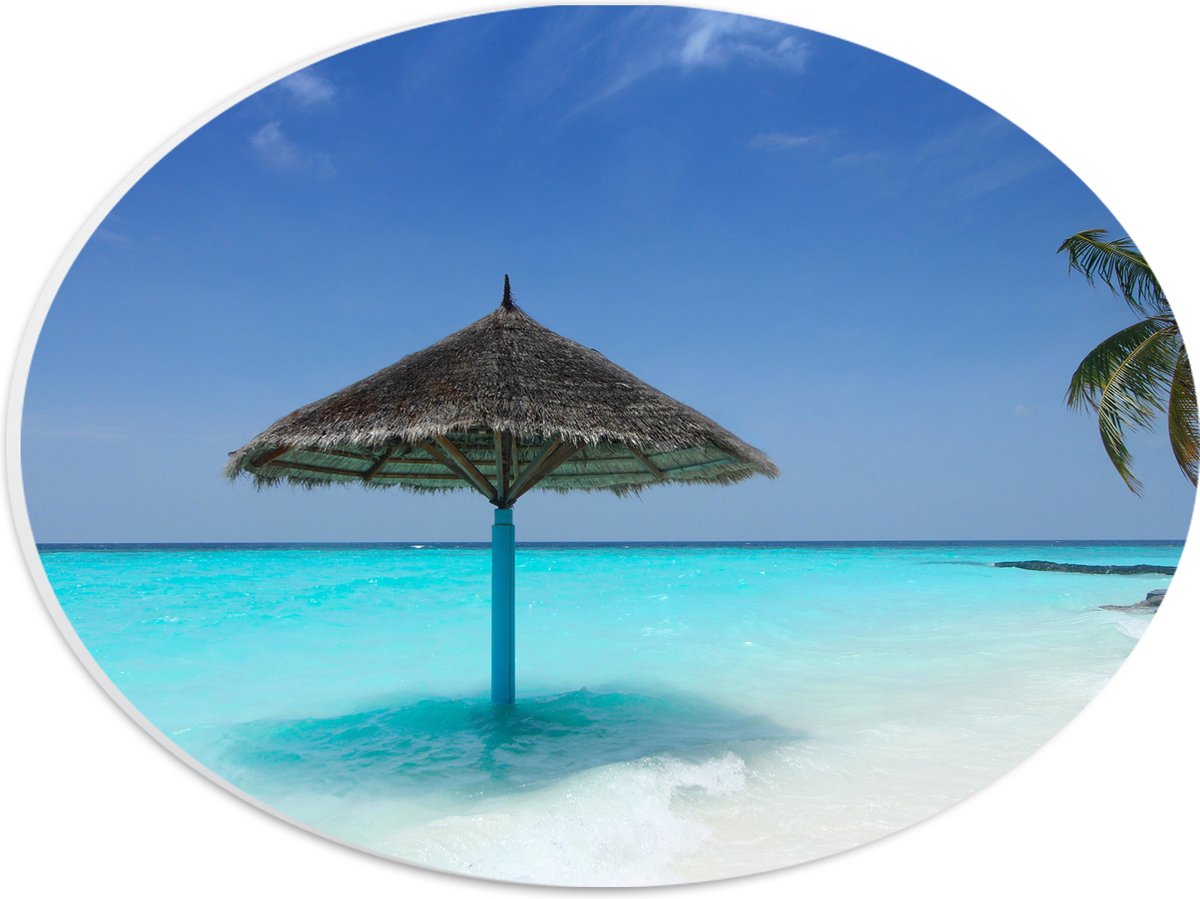 PVC Schuimplaat Ovaal - Rieten Parasol op het Strand bij het Blauwe Water - 28x21 cm Foto op Ovaal (Met Ophangsysteem)