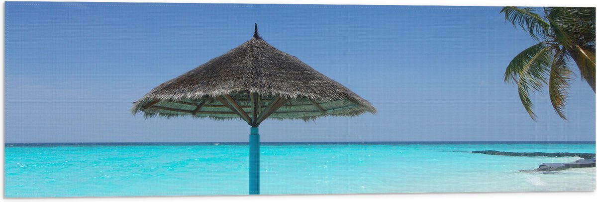 Vlag - Rieten Parasol op het Strand bij het Blauwe Water - 90x30 cm Foto op Polyester Vlag