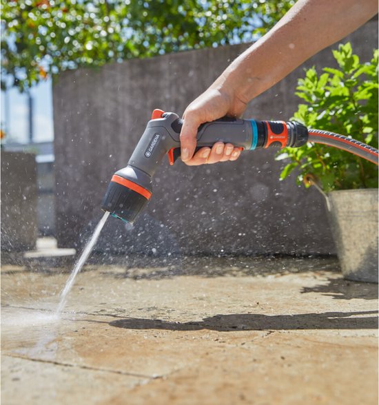 Hand sproeit een tegelvloer met een Gardena spuitpistool.