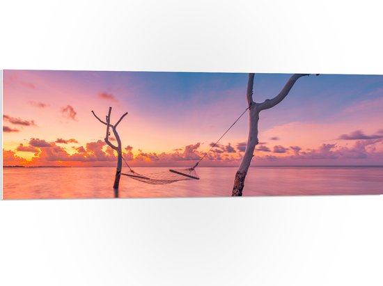 PVC Schuimplaat- Hangmat tussen Kale Takken in de Zee tijdens Zonsondergang - 120x40 cm Foto op PVC Schuimplaat