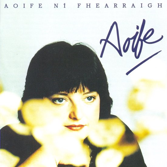 Aoife Ni Fhearraigh, een vrouw met zwart haar en een donker shirt, met haar naam in blauwe letters.