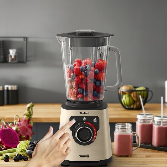 Gouden Tefal blender met bessen in de kan, een hand stelt de blender in.